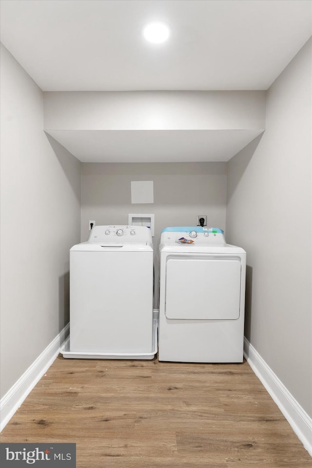 laundry room with washing machine and dryer and light hardwood / wood-style flooring