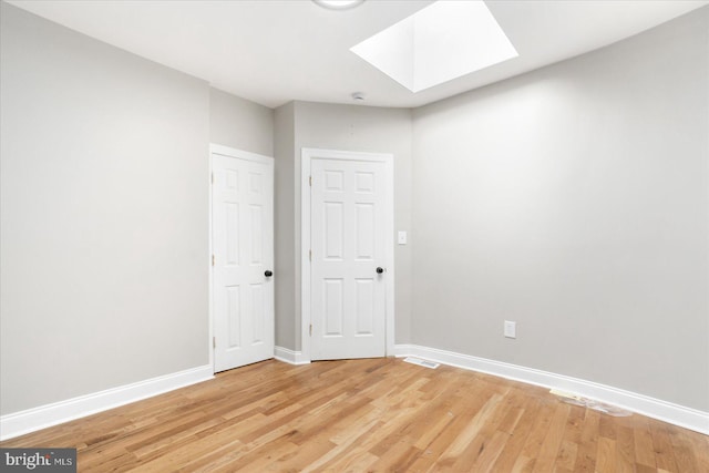 empty room with hardwood / wood-style flooring and a skylight