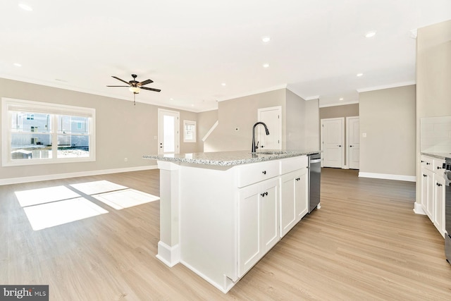 kitchen featuring sink, light hardwood / wood-style flooring, white cabinetry, and a kitchen island with sink