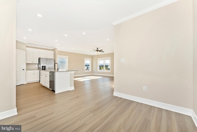 kitchen with light hardwood / wood-style flooring, appliances with stainless steel finishes, white cabinets, a kitchen island with sink, and ornamental molding