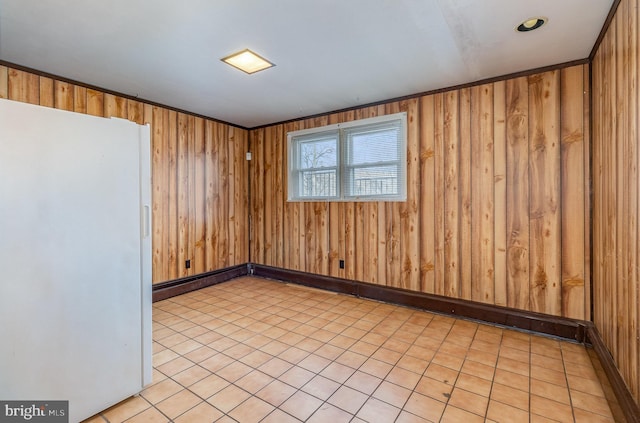 unfurnished room featuring ornamental molding and wooden walls