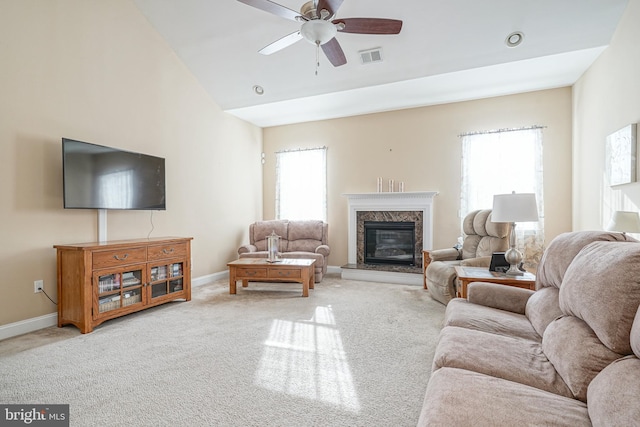 living room featuring ceiling fan, light carpet, a high end fireplace, baseboards, and vaulted ceiling