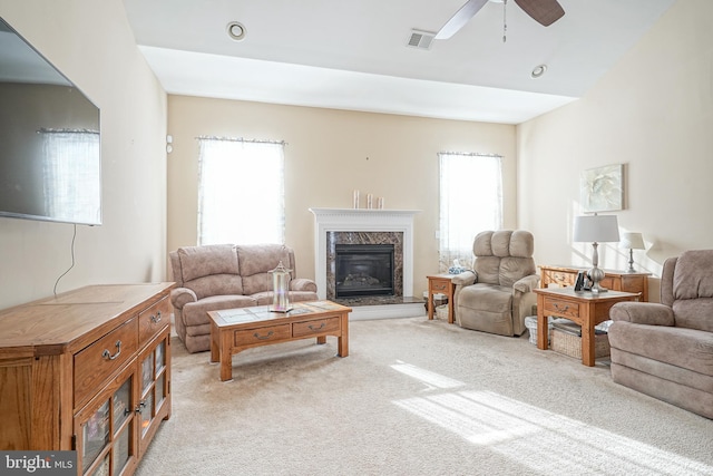 living area with light carpet, ceiling fan, a high end fireplace, and visible vents