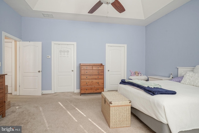 bedroom with light colored carpet, a tray ceiling, visible vents, and baseboards