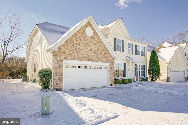 view of front of home with a garage, driveway, central AC unit, and stone siding