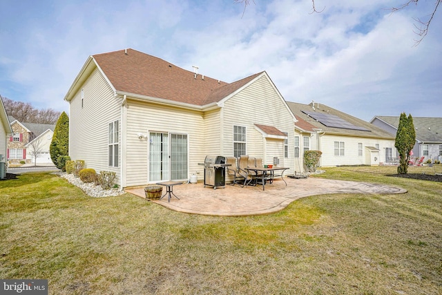 rear view of house with a patio, a yard, and a shingled roof