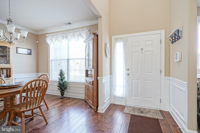 entryway featuring plenty of natural light, dark hardwood / wood-style flooring, ornamental molding, and a notable chandelier