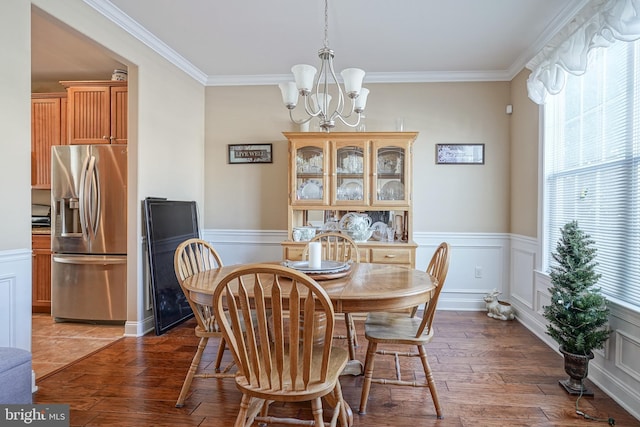 dining space with a wainscoted wall, crown molding, a chandelier, and hardwood / wood-style flooring