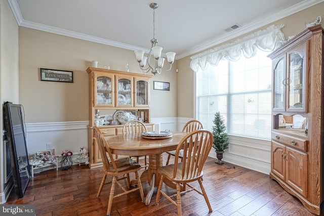 dining area with dark wood-style floors, wainscoting, visible vents, and crown molding