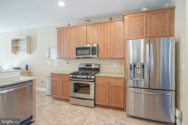 kitchen featuring recessed lighting, appliances with stainless steel finishes, brown cabinetry, light stone countertops, and baseboards