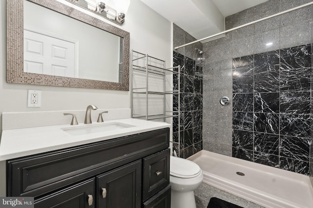 bathroom with vanity, toilet, and tiled shower