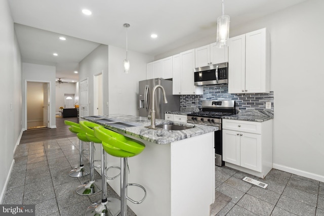 kitchen with white cabinetry, sink, ceiling fan, a kitchen island with sink, and appliances with stainless steel finishes