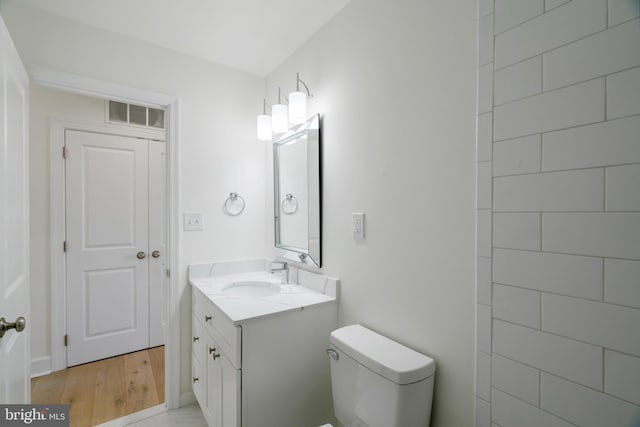 bathroom featuring wood-type flooring, vanity, and toilet