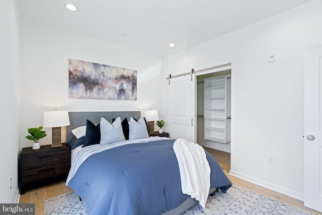 bedroom featuring a barn door, a closet, and light hardwood / wood-style flooring