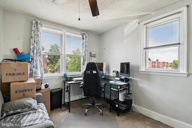 carpeted home office with ceiling fan and a textured ceiling