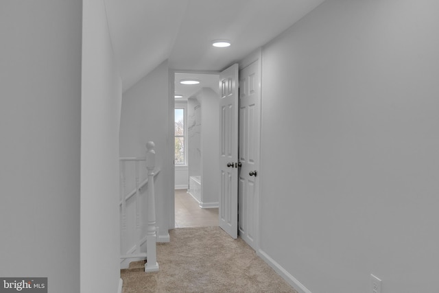 hall featuring light colored carpet and lofted ceiling