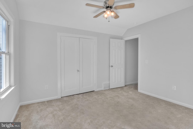 unfurnished bedroom with ceiling fan, light colored carpet, and lofted ceiling