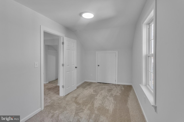 bonus room with light colored carpet and vaulted ceiling