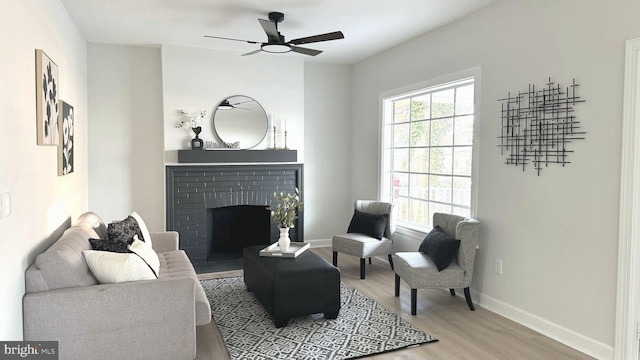 living room with hardwood / wood-style flooring, a brick fireplace, a wealth of natural light, and ceiling fan