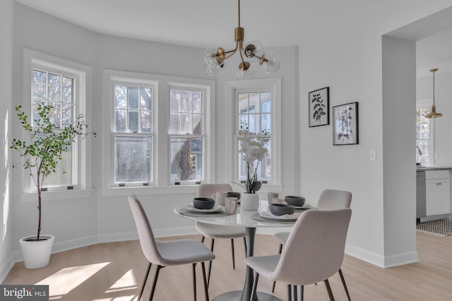 dining room featuring plenty of natural light, light wood-type flooring, and an inviting chandelier