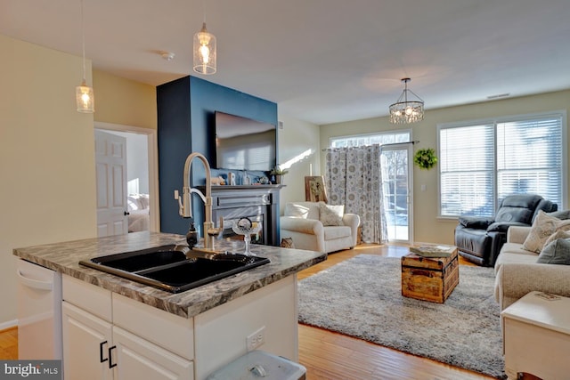 kitchen with a kitchen island with sink, sink, pendant lighting, dishwasher, and white cabinetry