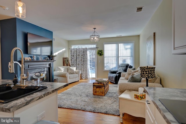 living room featuring sink, a chandelier, and light wood-type flooring