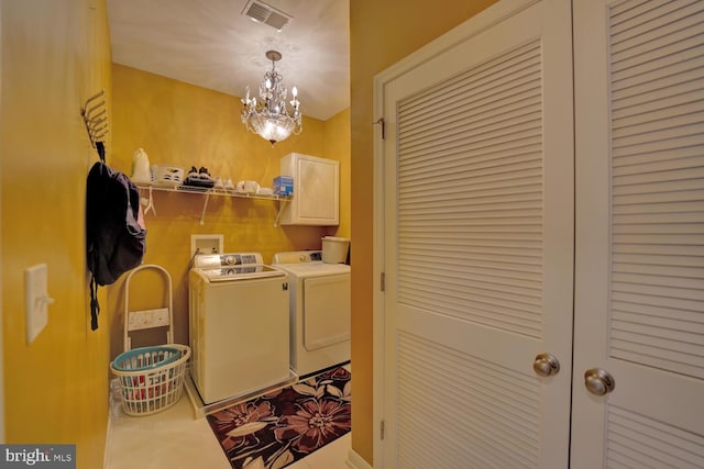 washroom with cabinets, tile patterned flooring, washing machine and dryer, and a chandelier