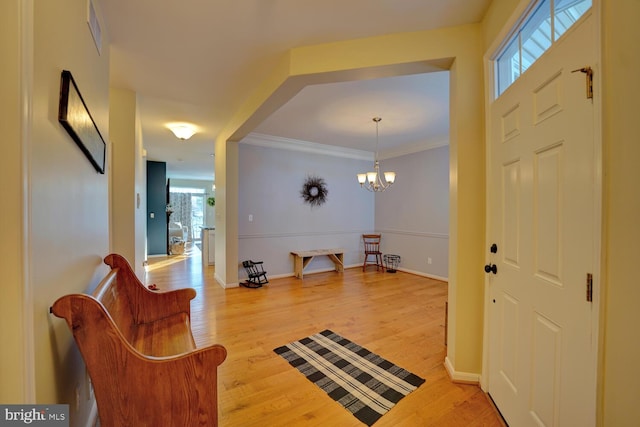 foyer entrance featuring hardwood / wood-style flooring, an inviting chandelier, and crown molding