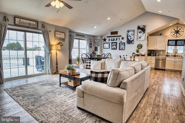 living room with light hardwood / wood-style floors, ceiling fan, lofted ceiling, and sink