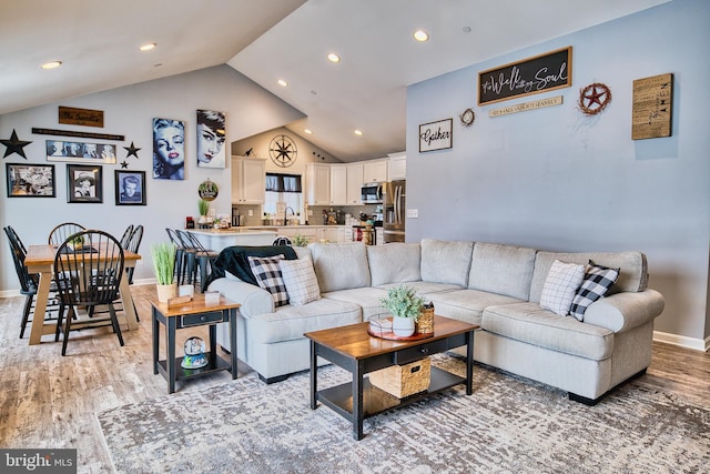 living room featuring sink, lofted ceiling, and hardwood / wood-style flooring