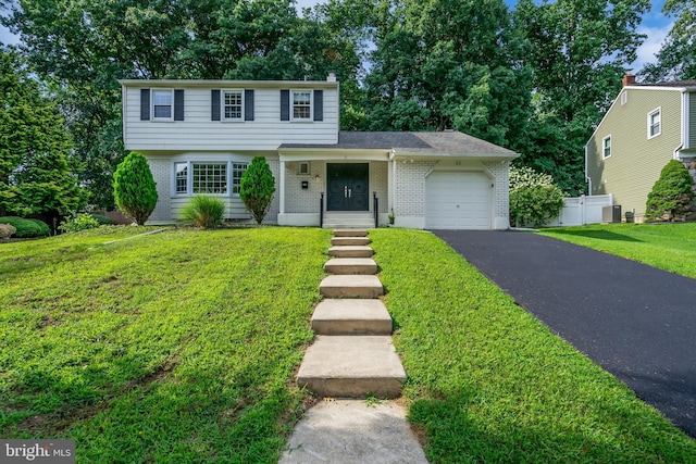 view of front of property with a front yard, a garage, and central AC unit