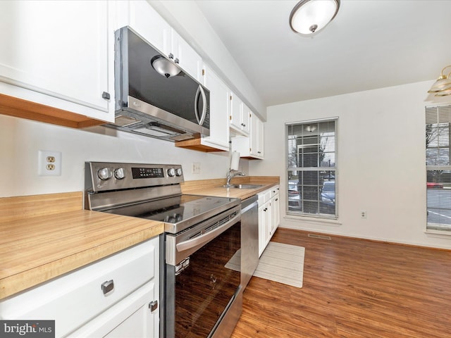 kitchen featuring white cabinets, appliances with stainless steel finishes, hardwood / wood-style floors, and sink