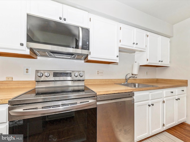 kitchen featuring white cabinets, light wood-type flooring, stainless steel appliances, and sink