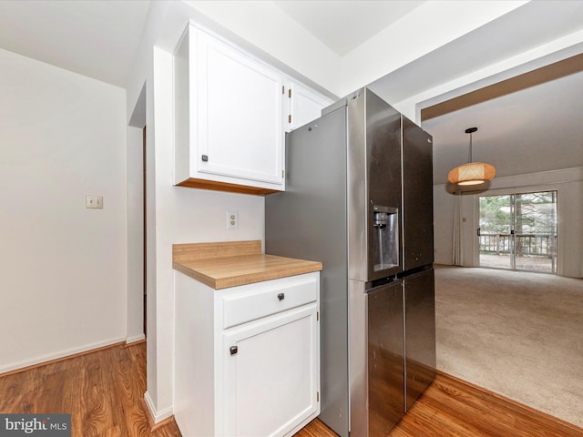 kitchen featuring decorative light fixtures, light wood-type flooring, white cabinetry, and stainless steel refrigerator with ice dispenser