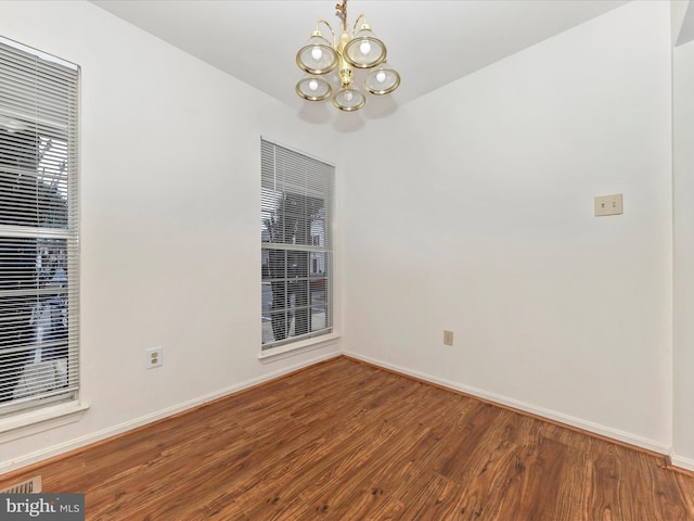 spare room with hardwood / wood-style flooring and a notable chandelier