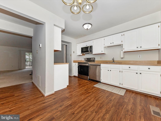 kitchen featuring appliances with stainless steel finishes, dark hardwood / wood-style flooring, white cabinetry, and sink