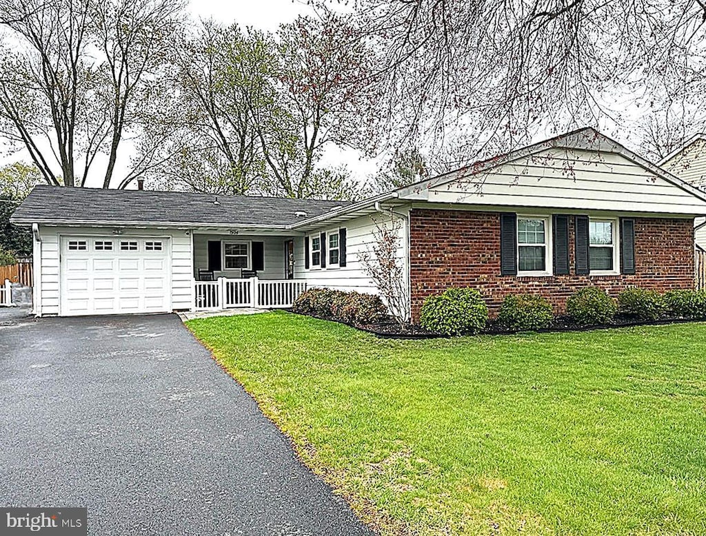 ranch-style house featuring a porch, a garage, and a front lawn