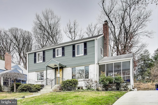 view of front of home with a front yard and a sunroom