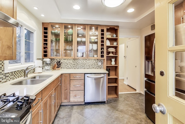 kitchen featuring dishwasher, a raised ceiling, gas range oven, sink, and extractor fan