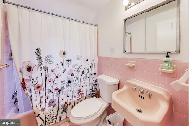 full bathroom with sink, shower / bath combo, tile walls, and toilet