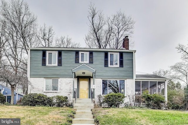 view of front of house with a front yard and a sunroom