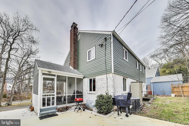 rear view of property with a patio area, a sunroom, and central AC unit