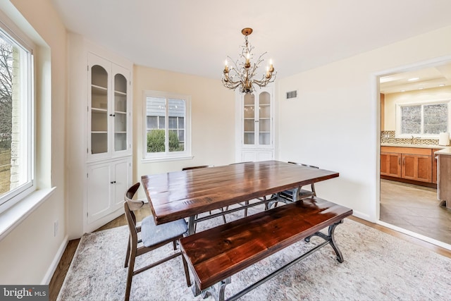 dining room featuring sink, a wealth of natural light, a chandelier, and light hardwood / wood-style floors