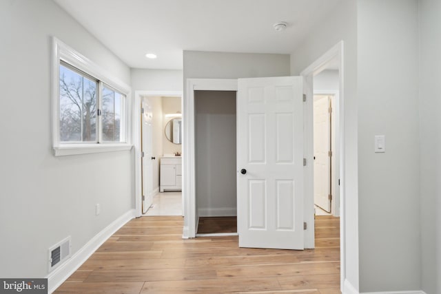 unfurnished bedroom with ensuite bath and light hardwood / wood-style floors