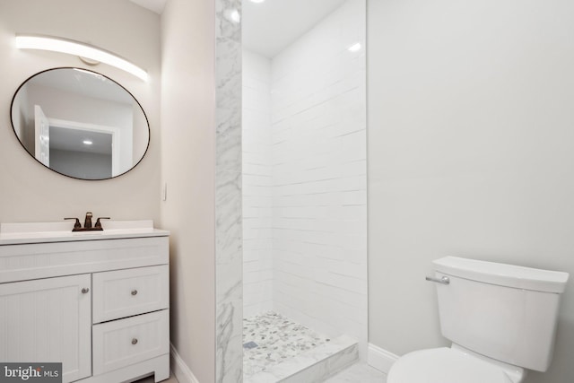 bathroom with vanity, tiled shower, and toilet