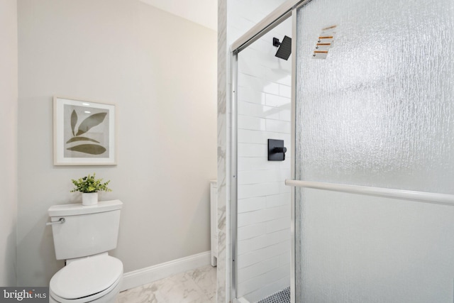 bathroom featuring a shower with door and toilet