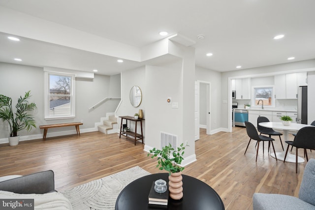 living room featuring sink, plenty of natural light, and light hardwood / wood-style floors