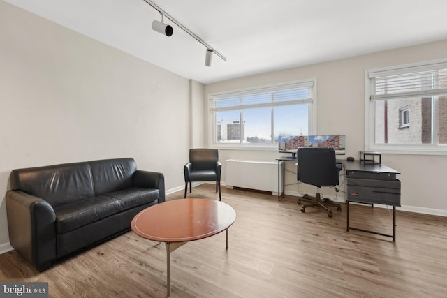 home office with light wood-type flooring and rail lighting