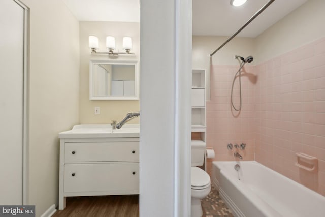 full bathroom with vanity, wood-type flooring, tiled shower / bath combo, and toilet