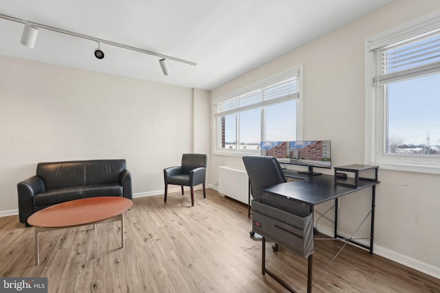 office area with rail lighting and light hardwood / wood-style floors